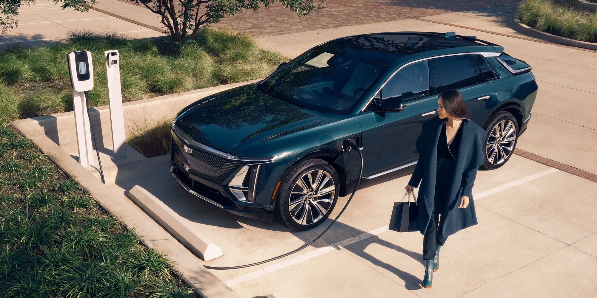 A woman looks at a 2025 Cadillac Lyriq being charged