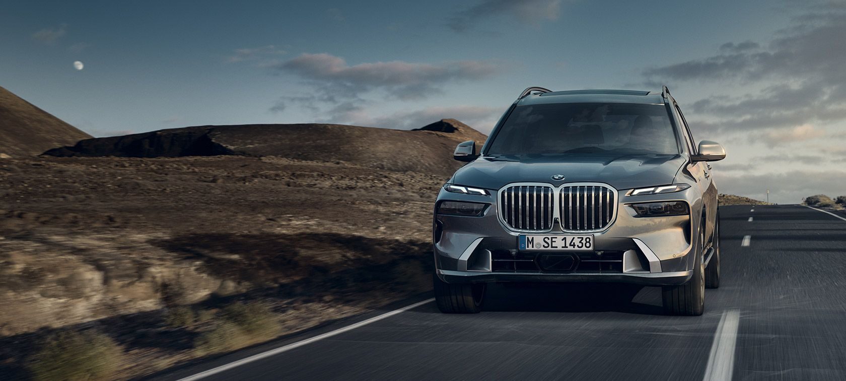 2025 BMW X7 in dark gray, luxury SUV on a desert mountain road.